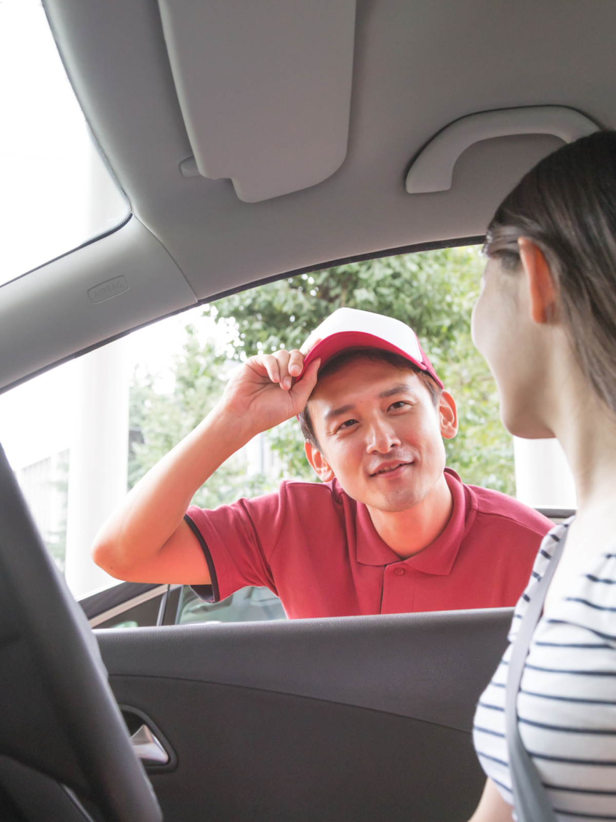 ガソリンスタンドのスタッフが車に乗った女性に話しかけている様子