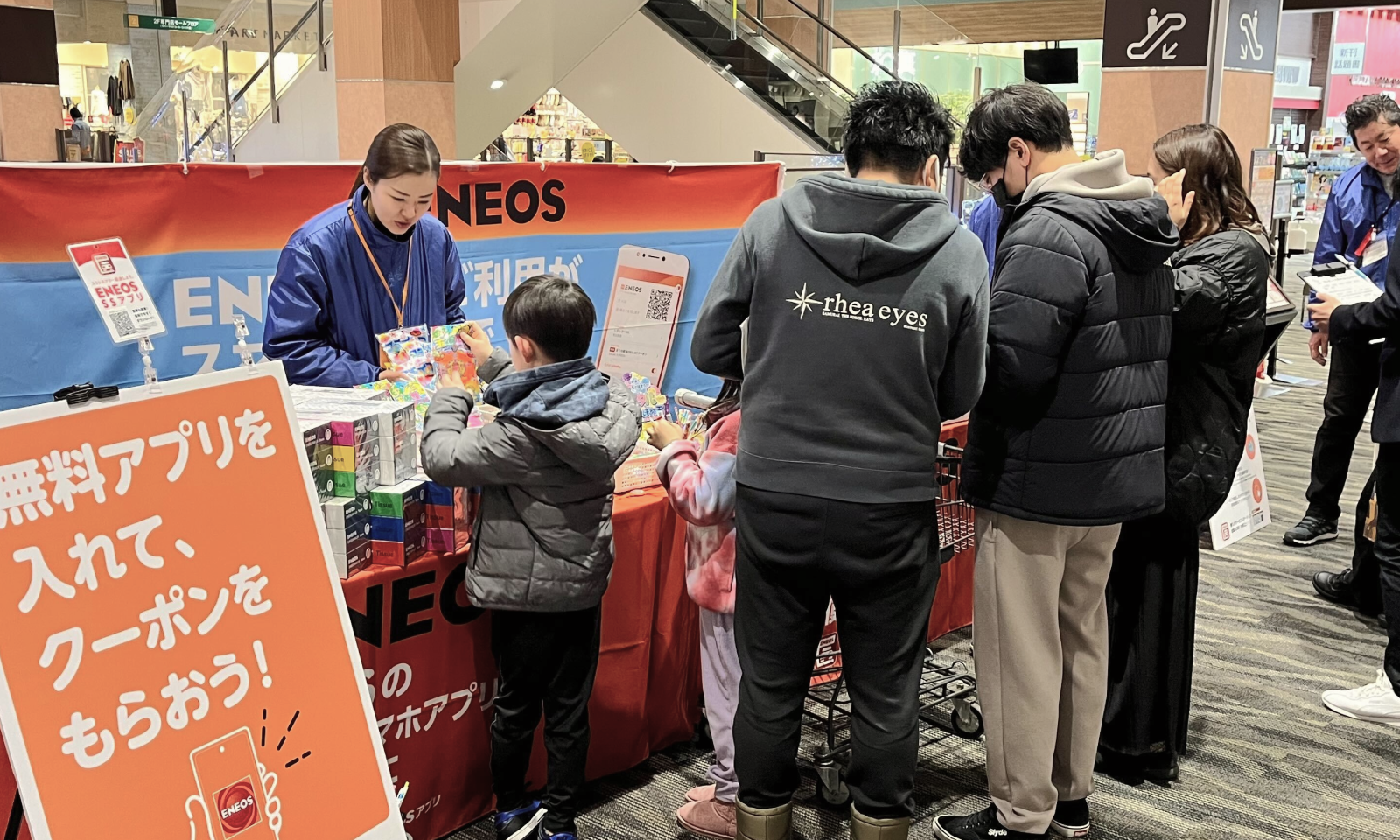 イベントでスタッフが子どもに景品を渡しており、その隣ではスタッフがお客様にアンケートを取っている様子